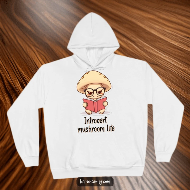 Funny hoodie with a grumpy mushroom wearing glasses, deeply engrossed in reading a tiny book, offering cozy wisdom.