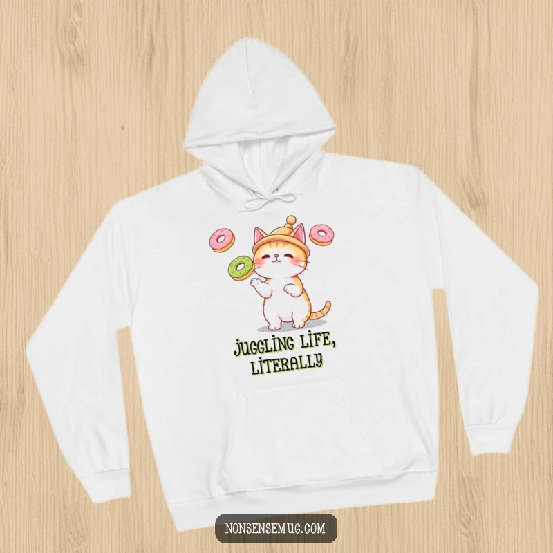 Funny hoodie showing a cat in a tiny hat, juggling three floating donuts, an excellent choice for a humorous gift.