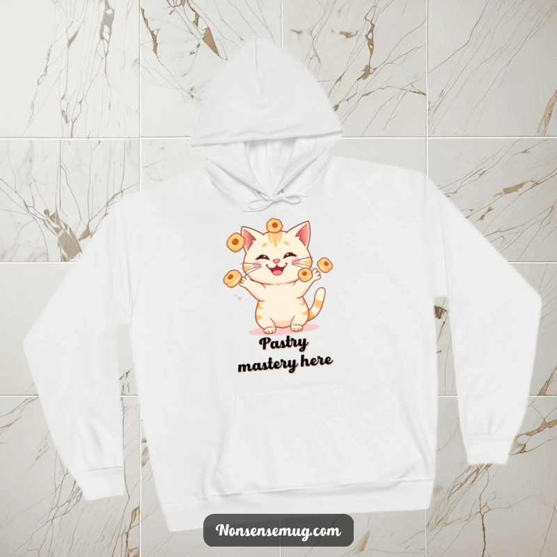 Funny cat juggling sentient breakfast pastries with a silly grin, on a soft and warm hoodie. A humorous and comfortable apparel choice.