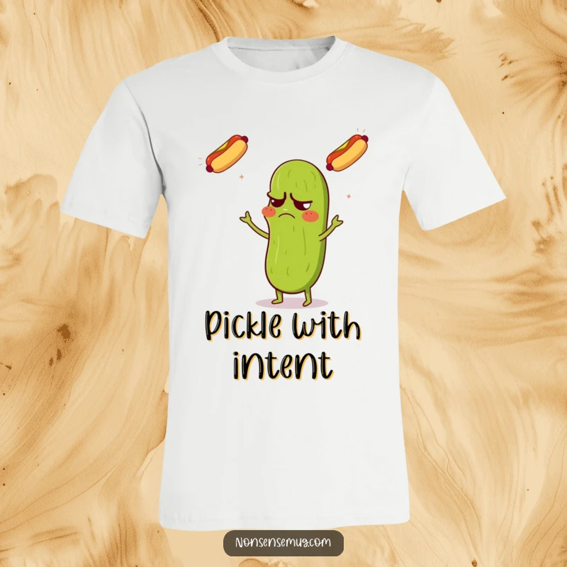 Funny t-shirt featuring a grumpy pickle with a confused expression, juggling three flying hot dogs with surprising skill.