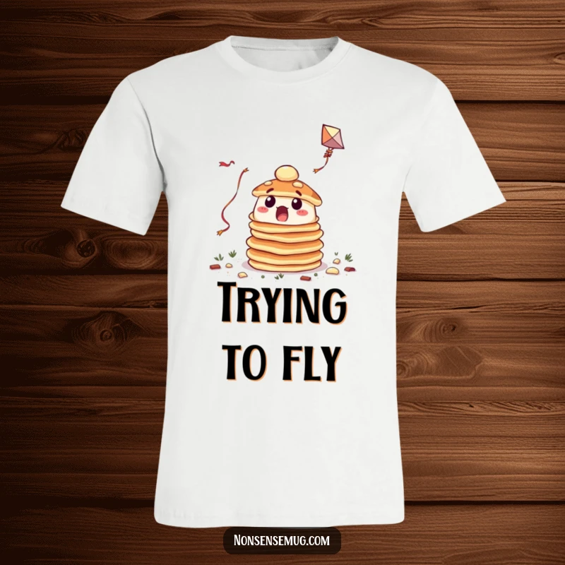 Funny t-shirt depicting a surprised pancake stack struggling to fly a kite, showcasing breakfast's funny side.